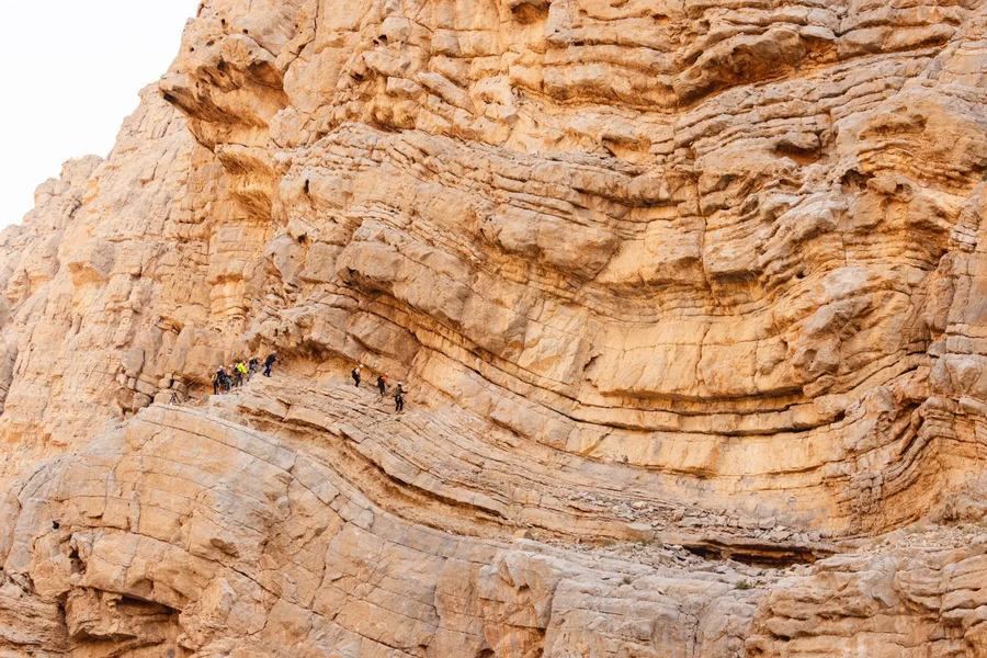 Climbers on the layered cliff faces of Jebel Jais